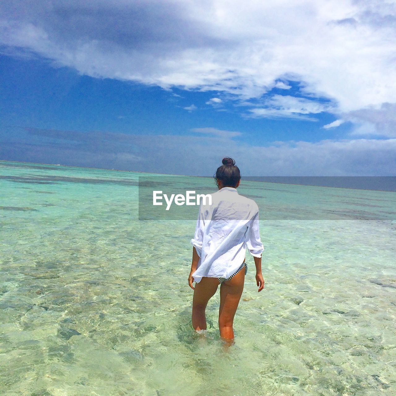 Rear view of woman walking in water at beach