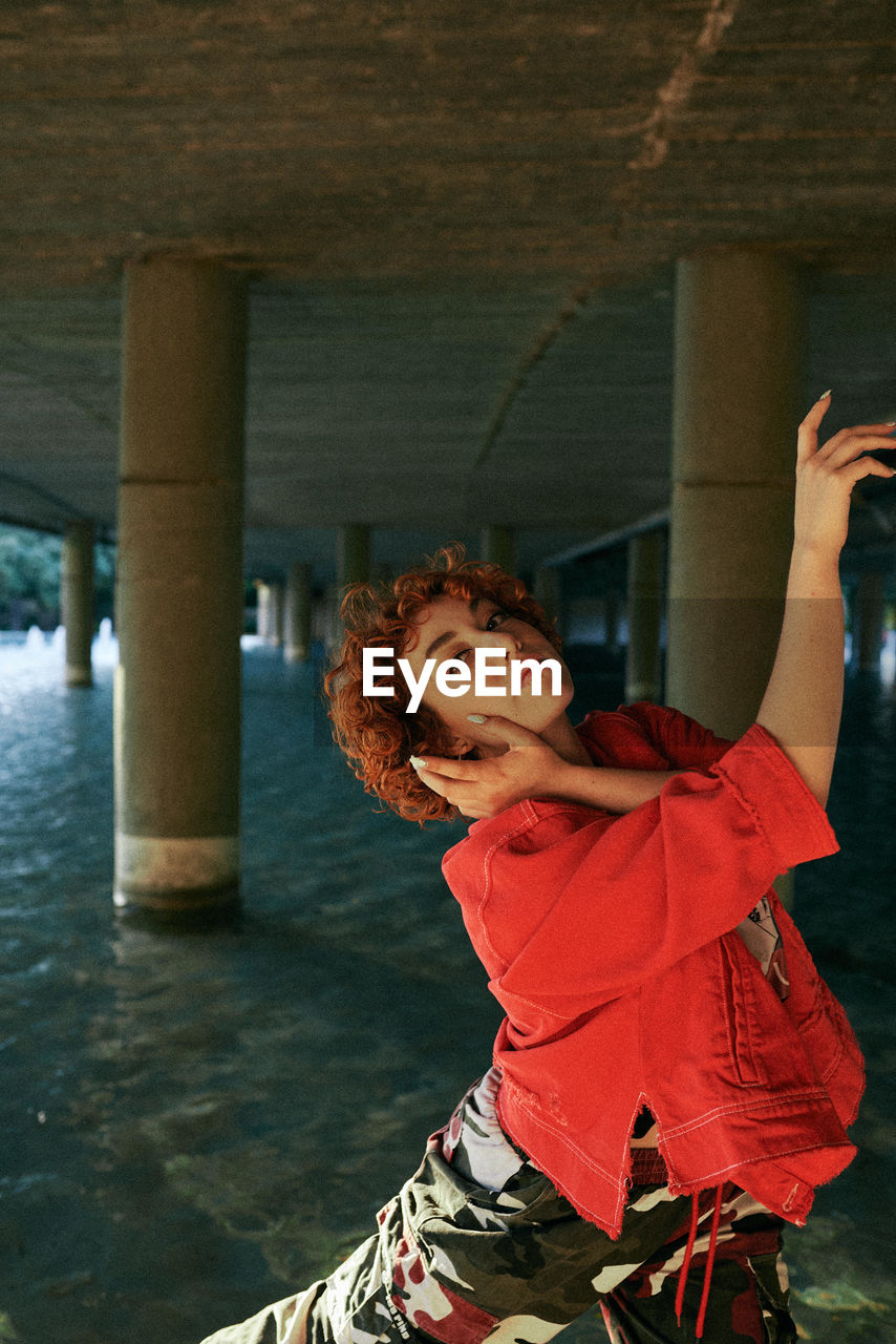 Curly redhead young female dancing with red jacket