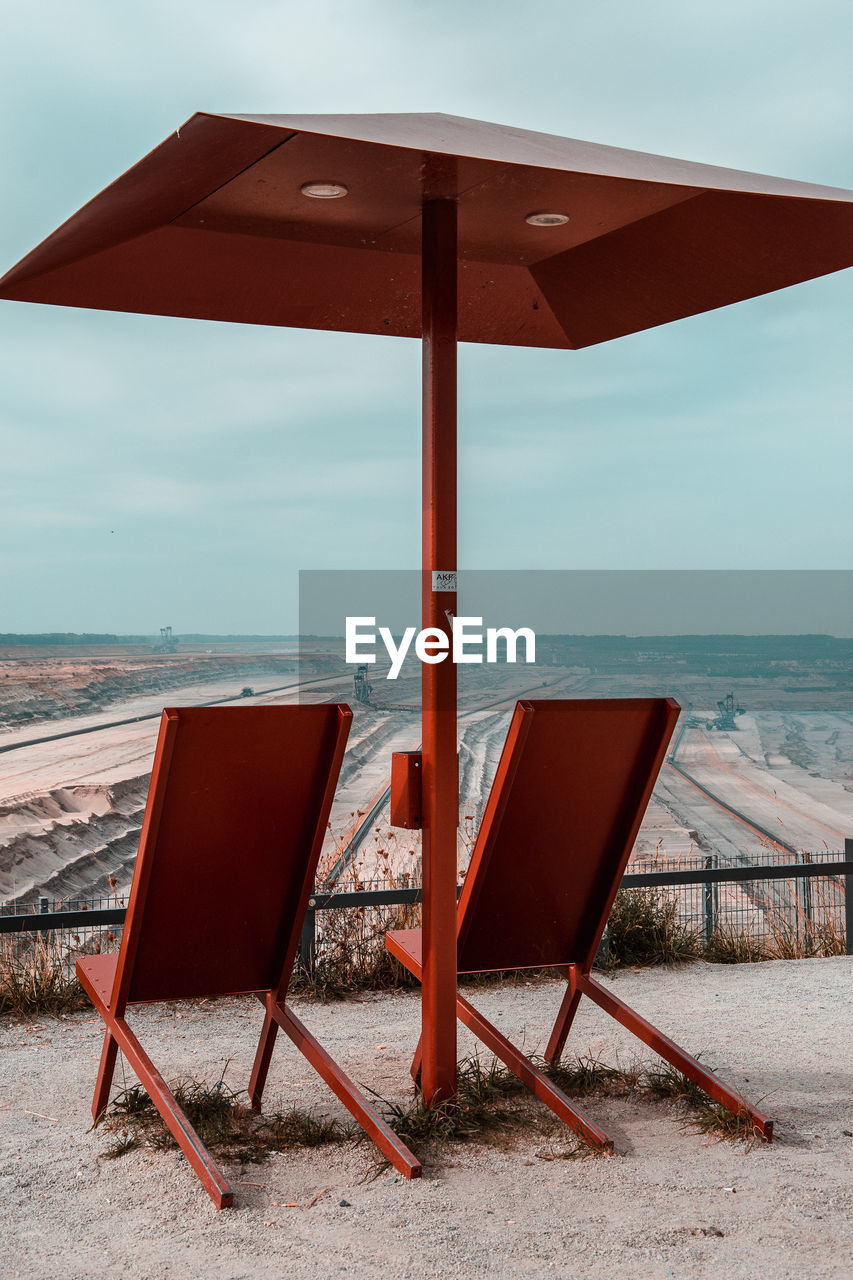 Deck chairs on beach against sky