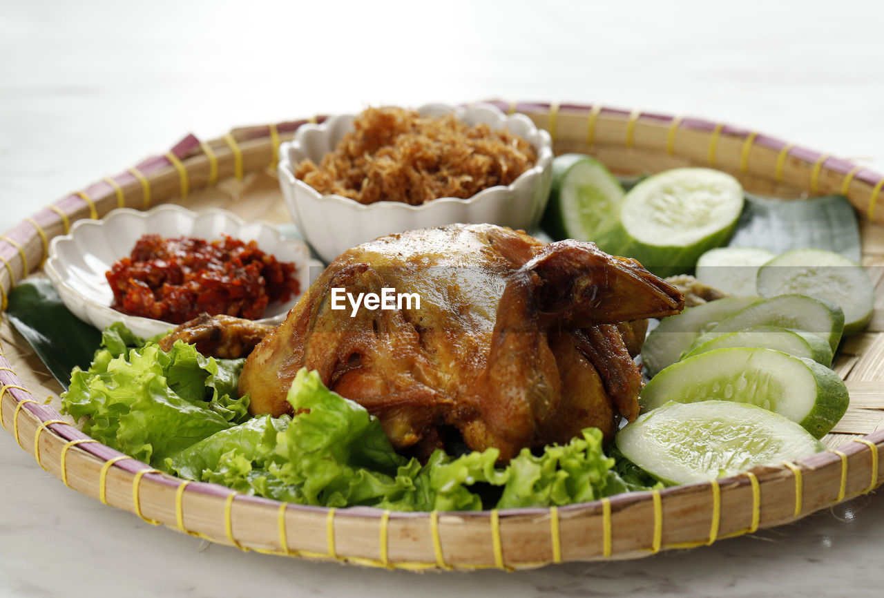 Ayam goreng utuh. deep fried whole chicken served with sambal chilli paste and fresh vegetable. 