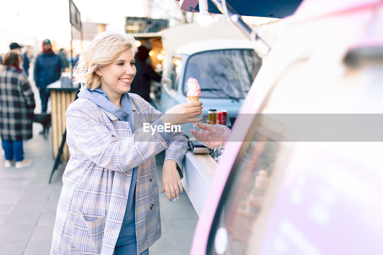 Smiling woman buying ice cream outdoors