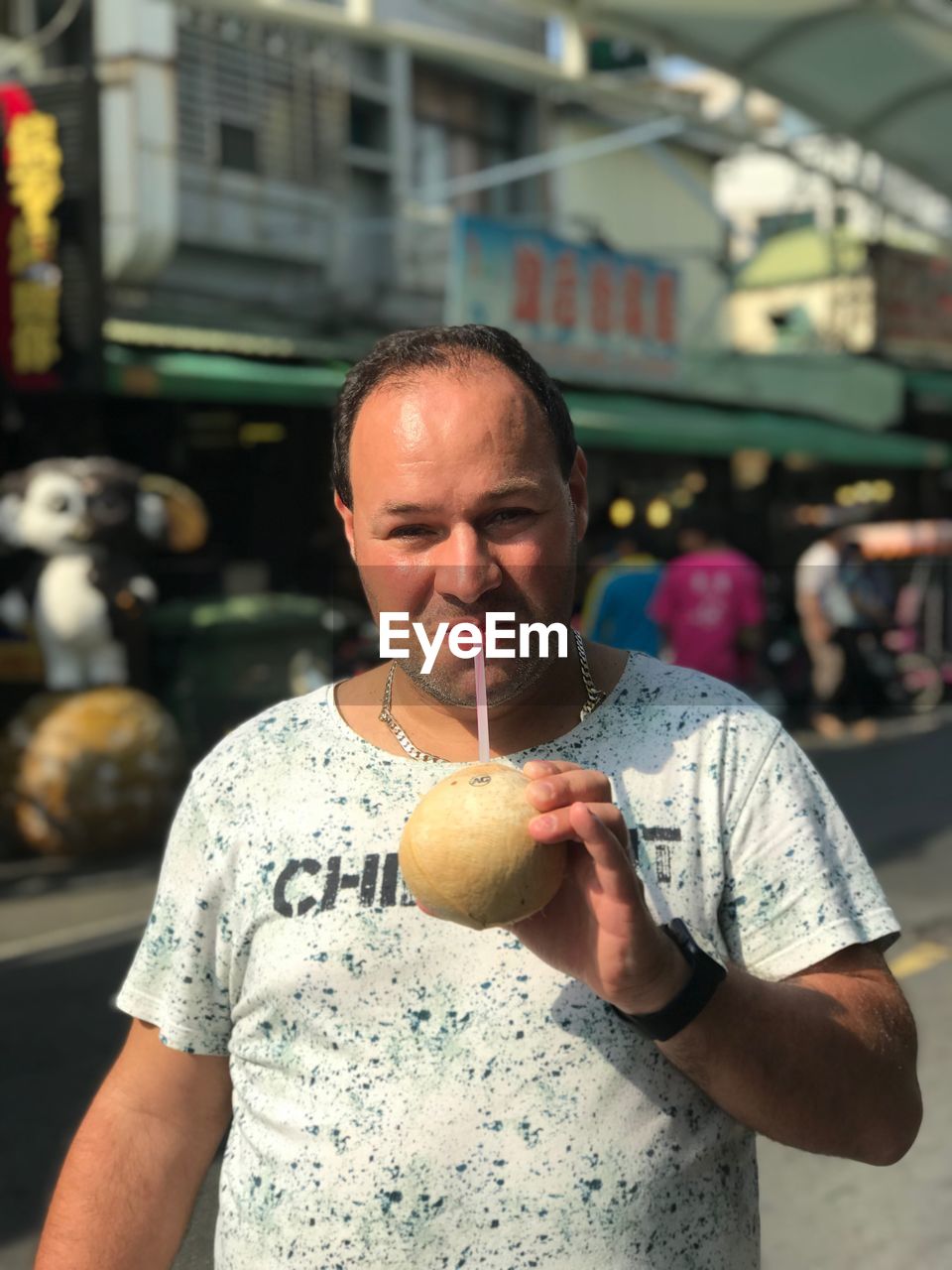 Portrait of mid adult man having drink while standing on street in city