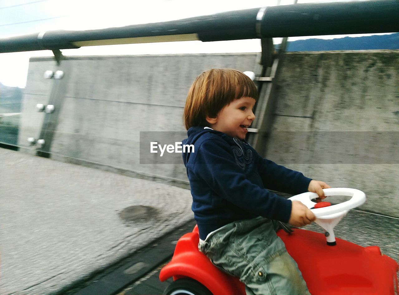 Happy boy driving toy car on road