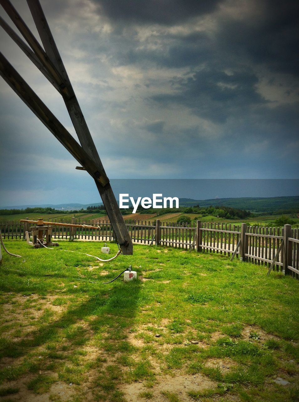 Electricity pylon on grassy field against cloudy sky