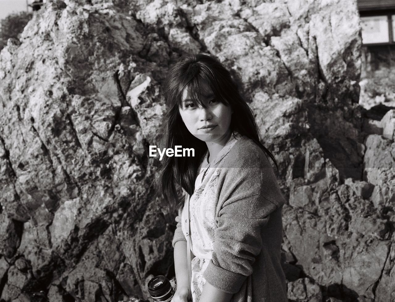 Portrait of woman standing against rock