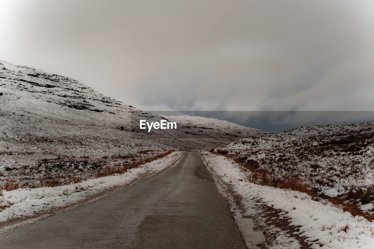 Road leading towards snowcapped mountain against sky