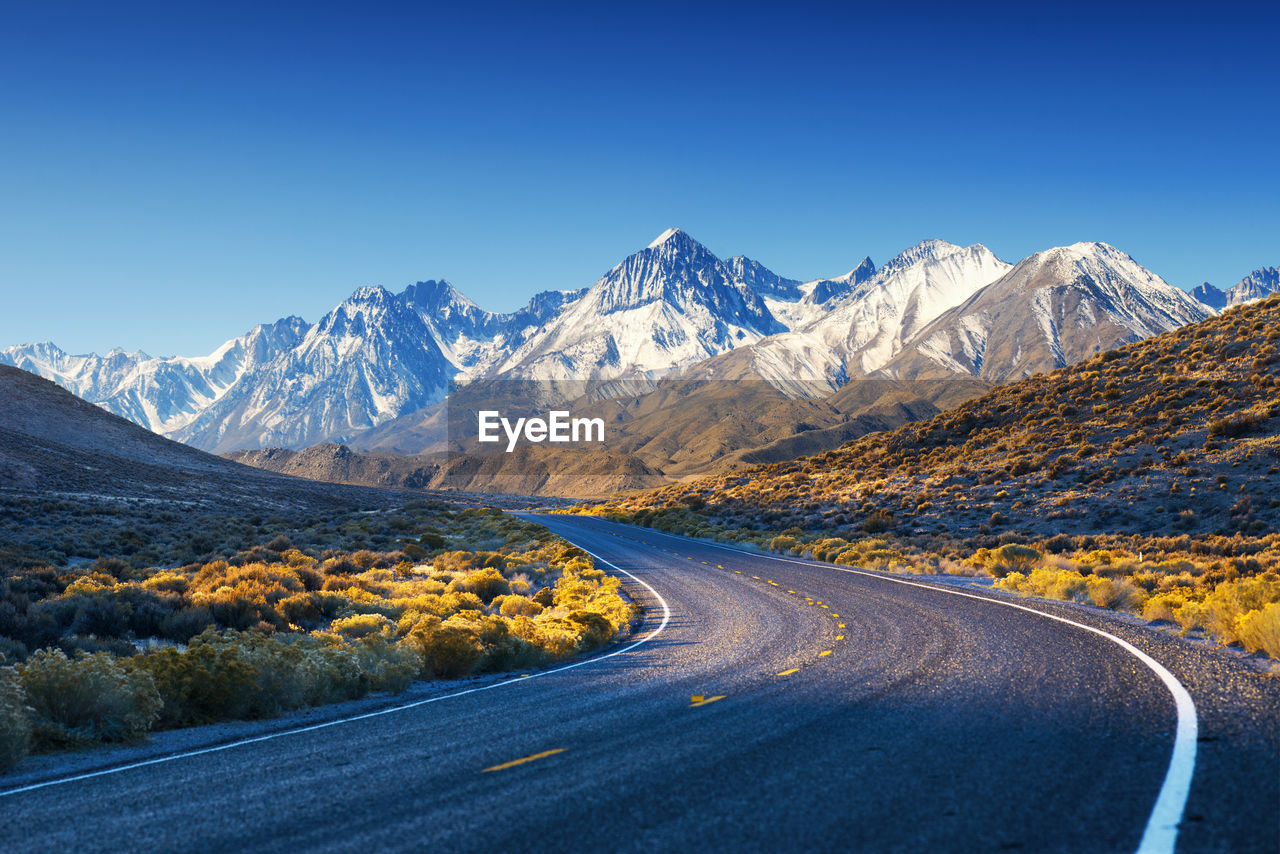 Road by mountains against clear blue sky