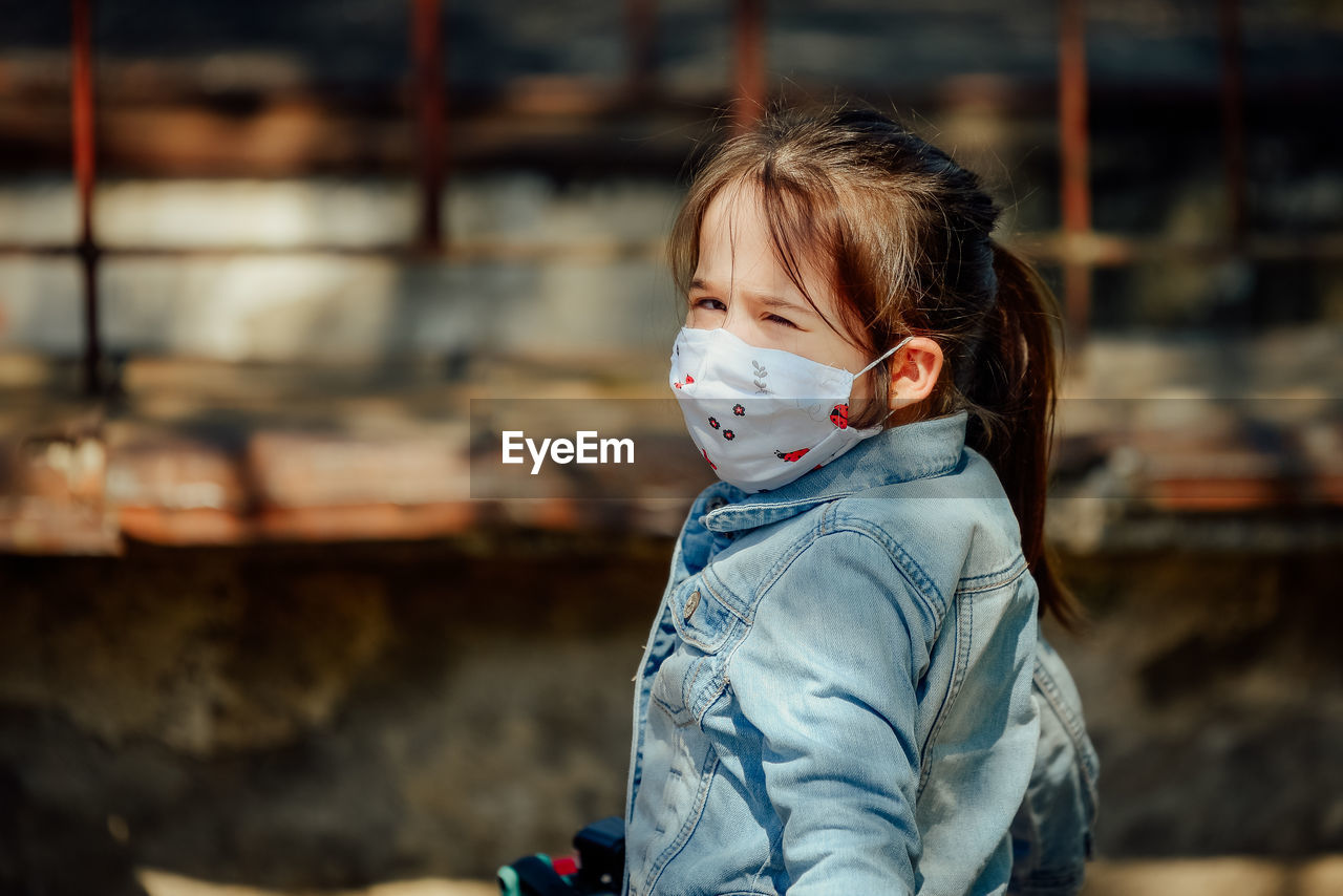 Portrait of cute girl wearing mask outdoors