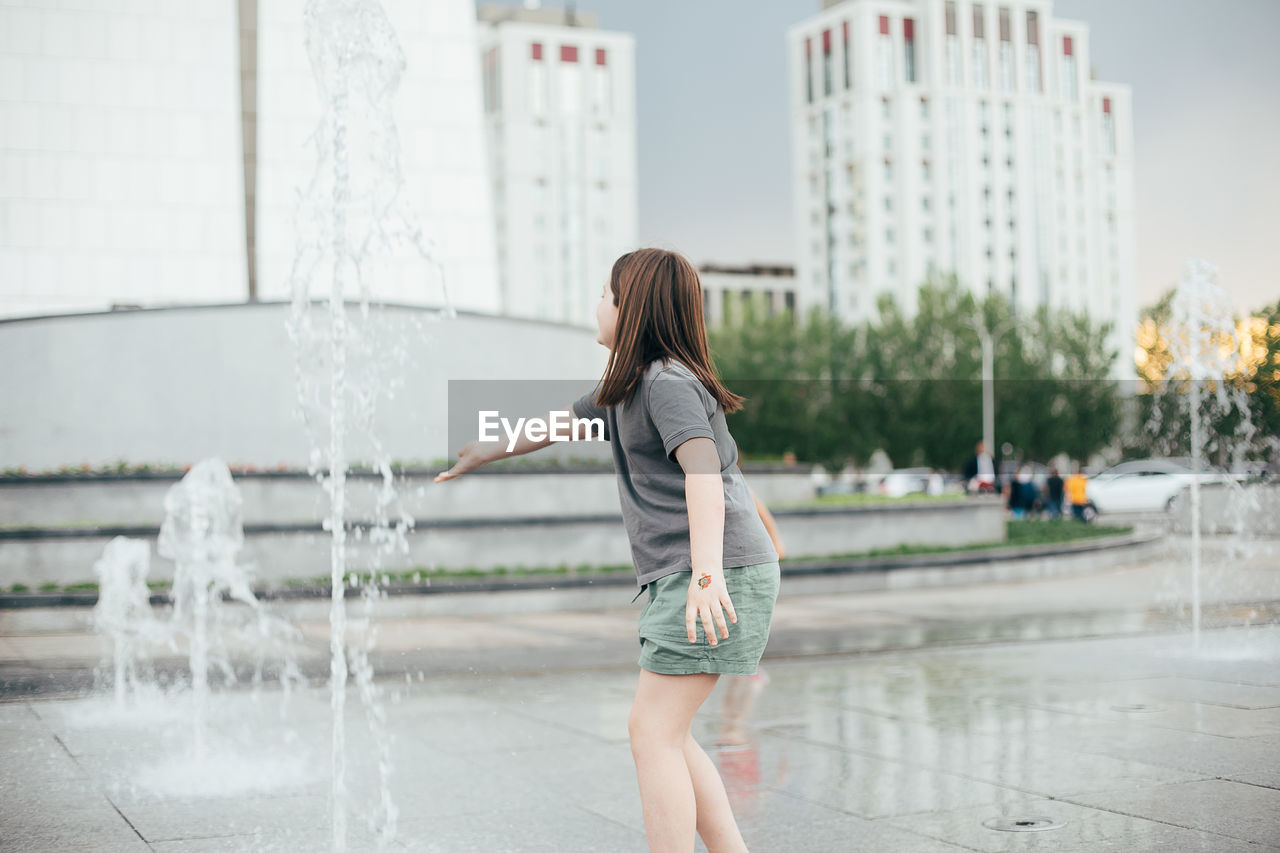 FULL LENGTH OF WOMAN STANDING AGAINST WATER