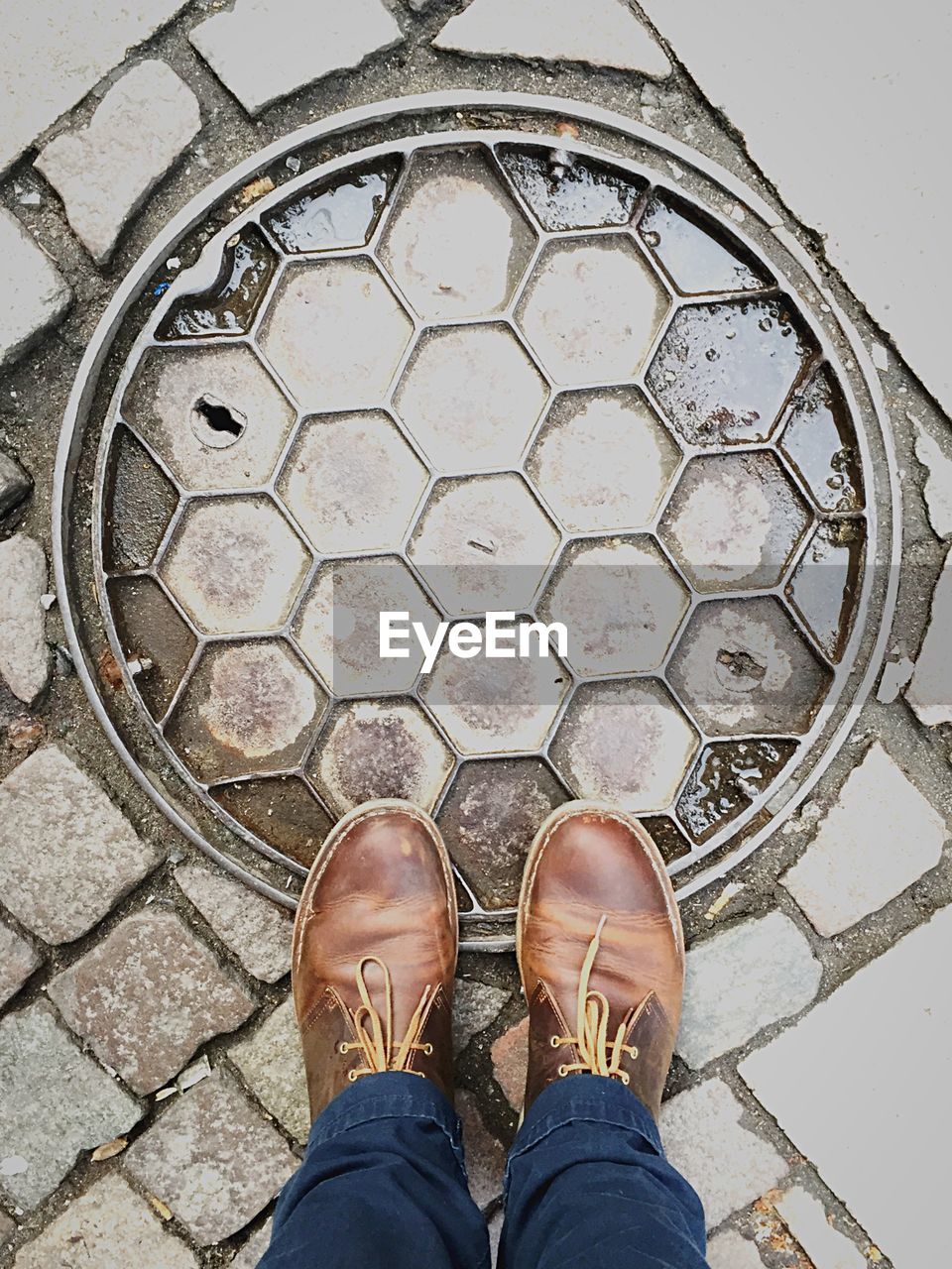 High angle low section of man standing on manhole