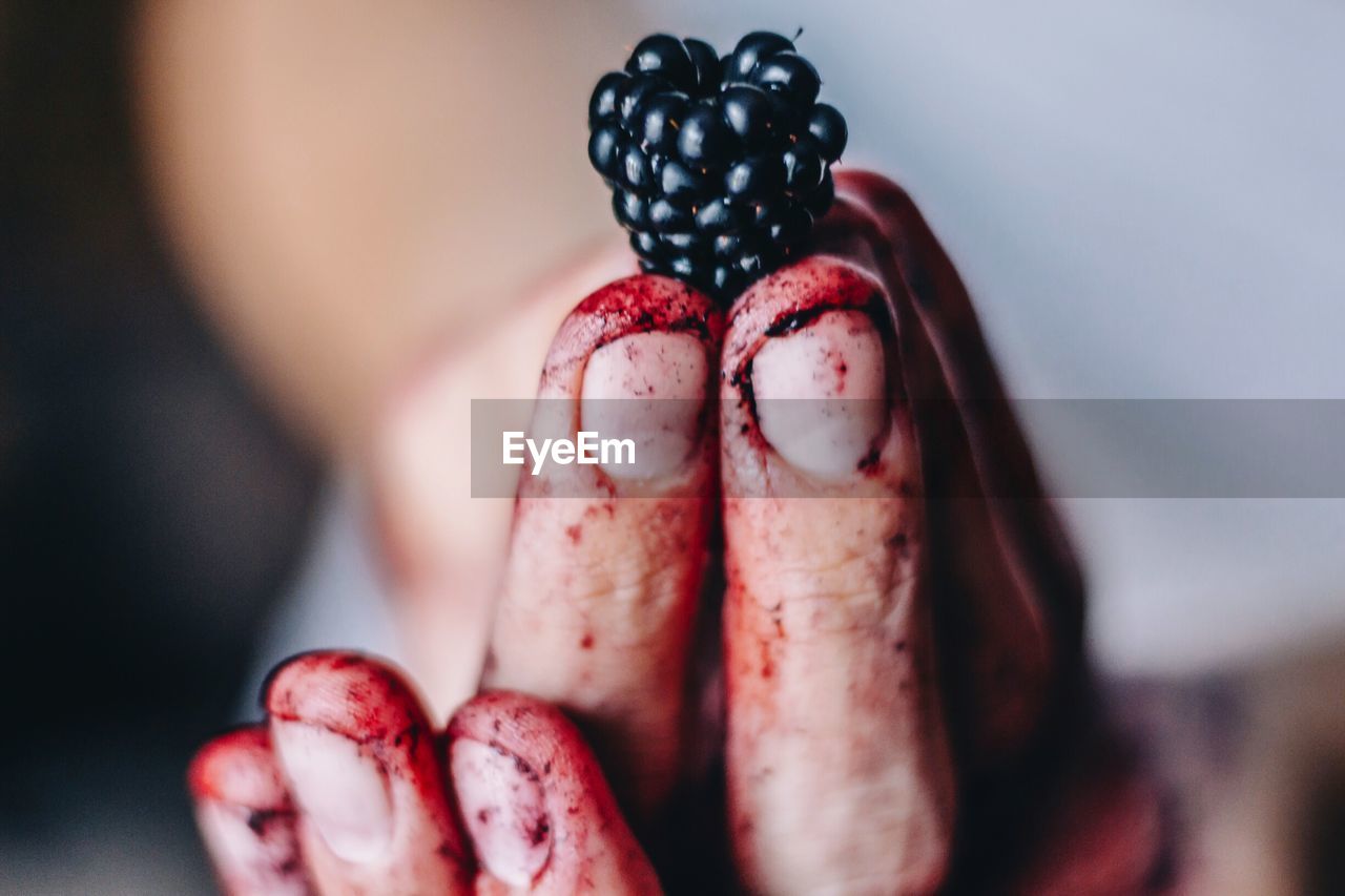 Cropped image of dirty hand holding blackberry