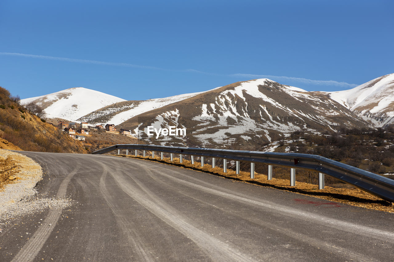 Road amidst snowcapped mountains against sky