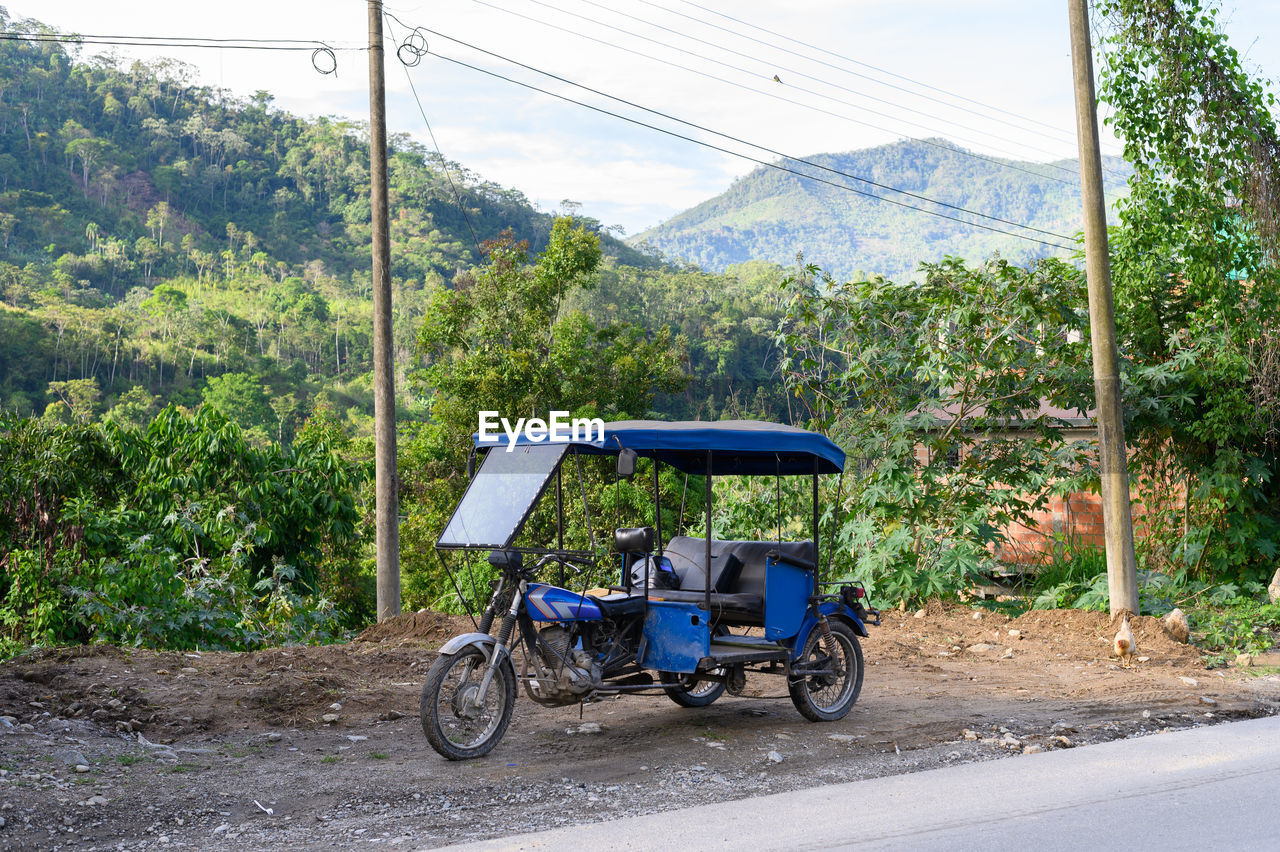 transportation, mode of transportation, road, tree, vehicle, plant, rickshaw, nature, travel, land vehicle, mountain, landscape, day, city, street, outdoors, jinrikisha, land, environment, driving, travel destinations, car, rural scene, sky, motion