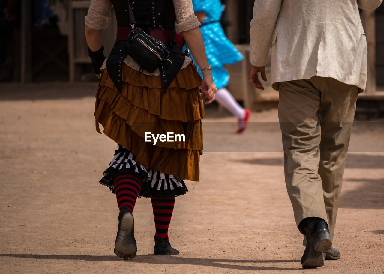 Low section of couple walking with road