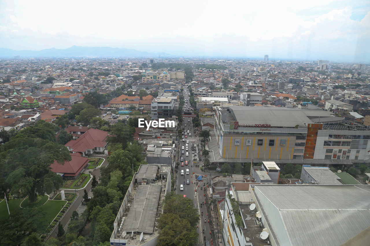 HIGH ANGLE VIEW OF STREET AMIDST BUILDINGS AGAINST SKY