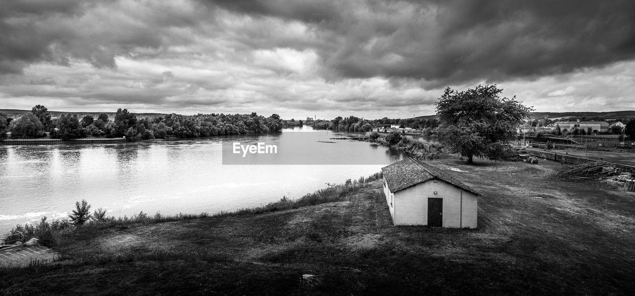 Houses by trees and buildings against sky. loneliness concept. black and white picture