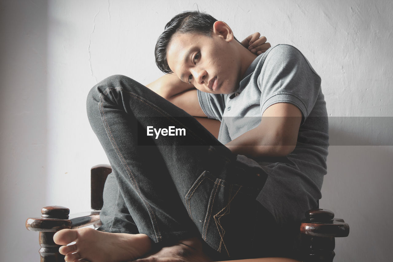 Portrait of teenage boy sitting on chair at home