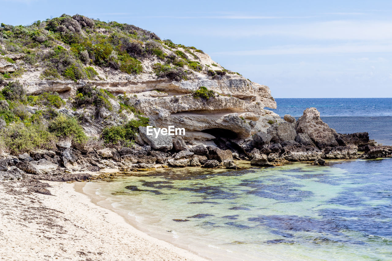 ROCK FORMATIONS ON SHORE AGAINST SKY