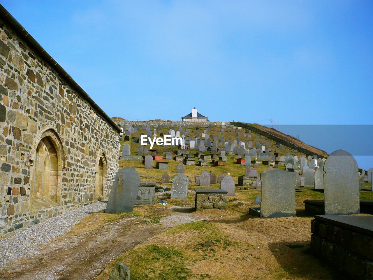 House by cemetery against clear blue sky