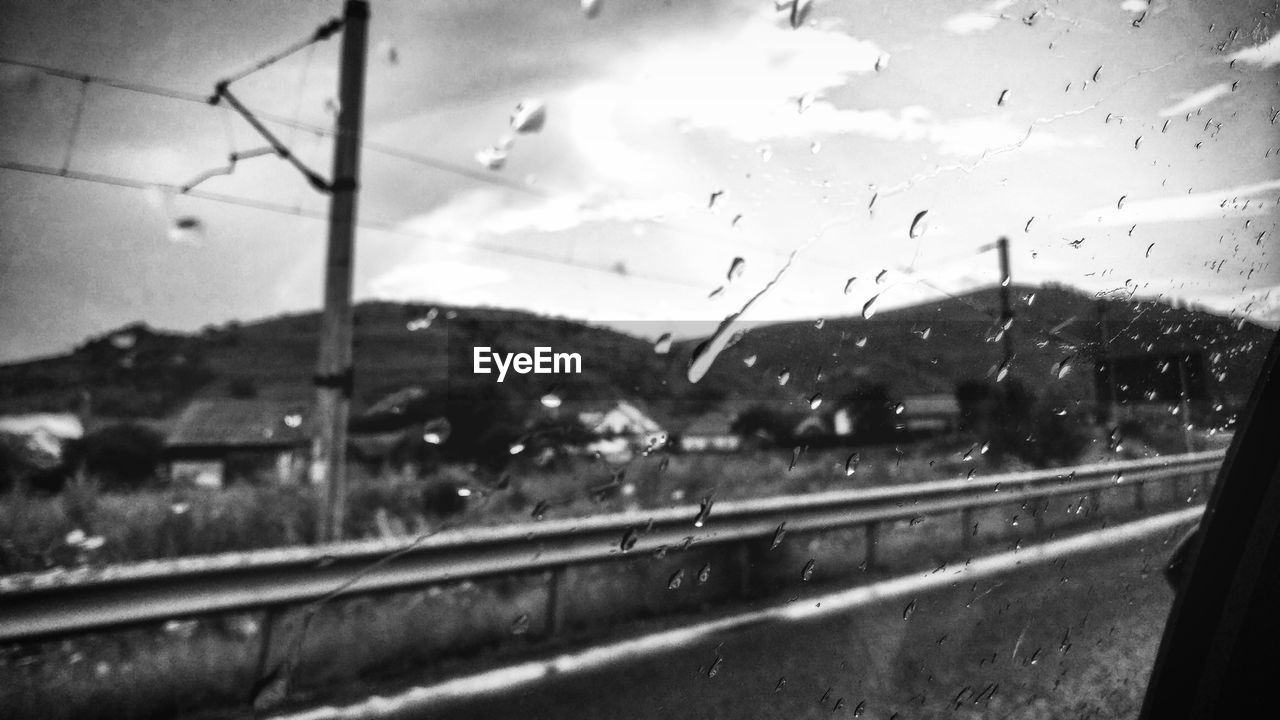 RAINDROPS ON GLASS WINDOW OF ROAD