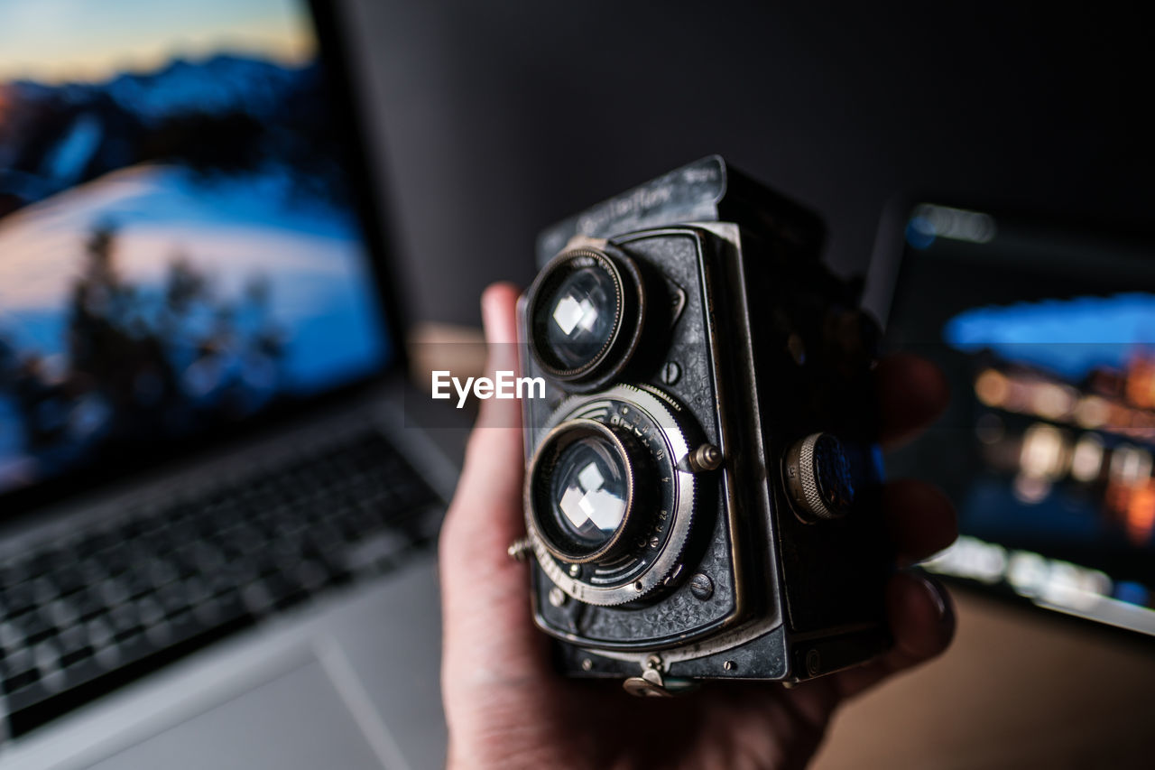 Cropped image of person holding digital camera indoors