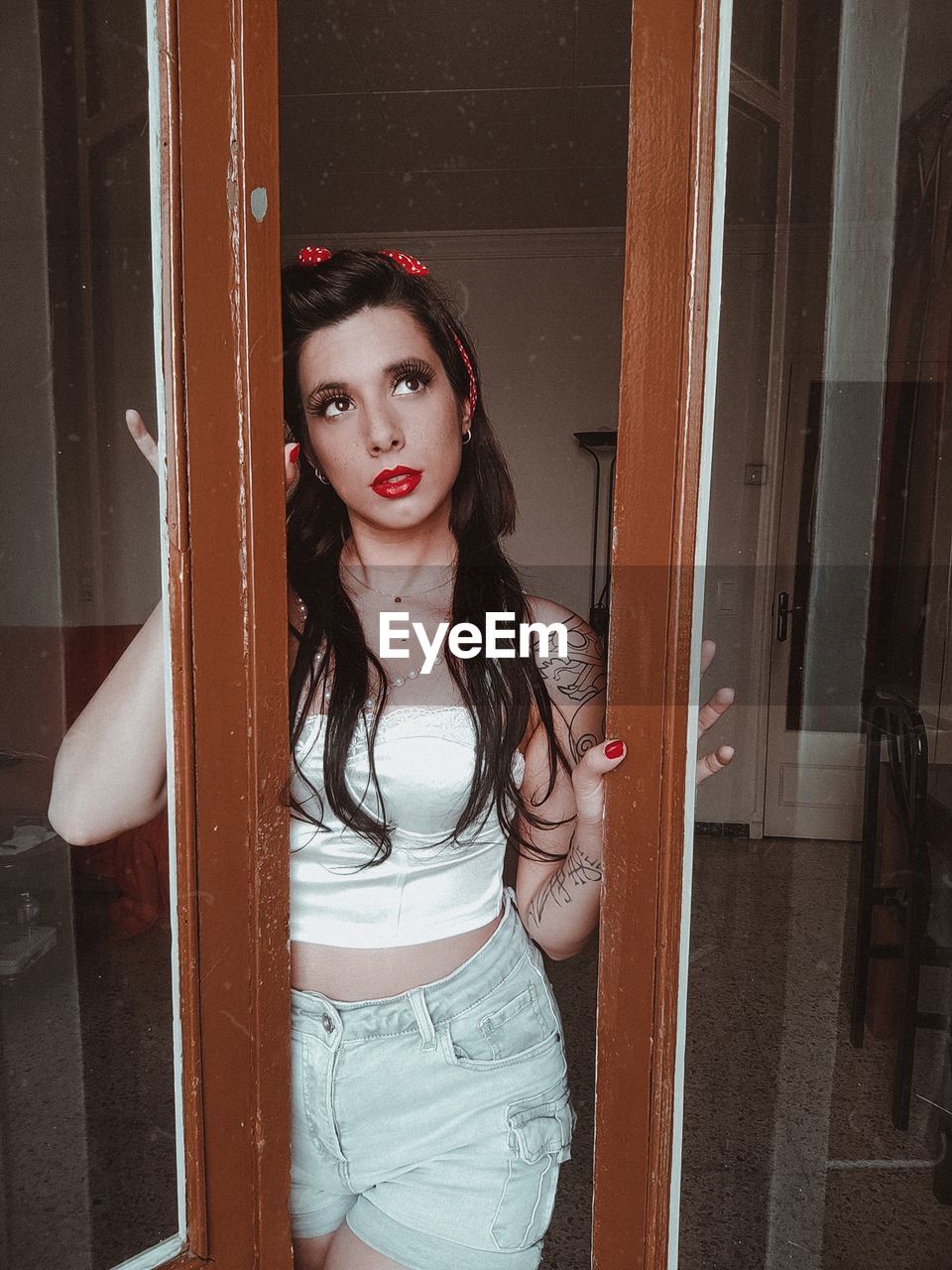 Portrait of young woman standing by window