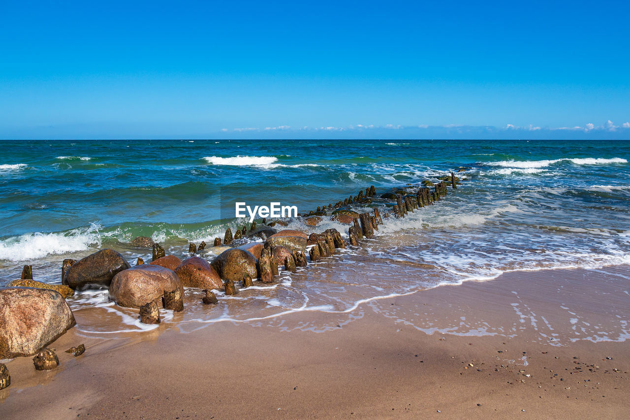 SCENIC VIEW OF BEACH AGAINST BLUE SKY