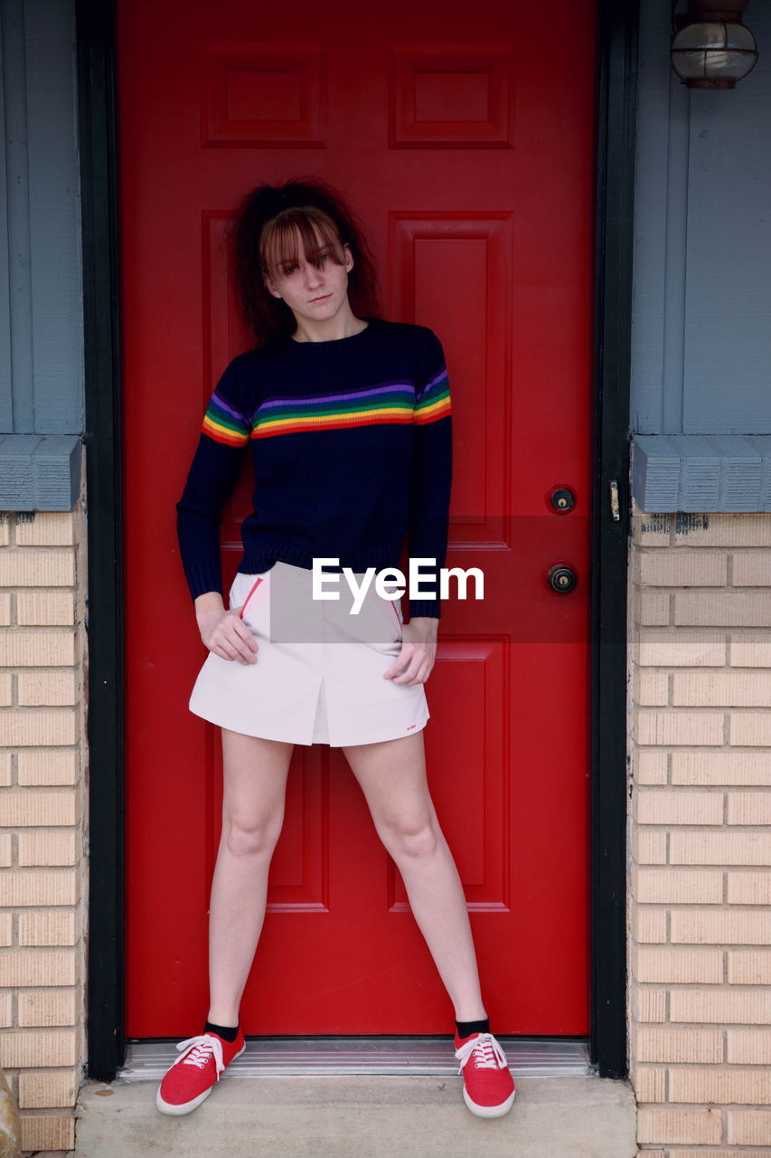 Portrait of teenage girl standing by red door