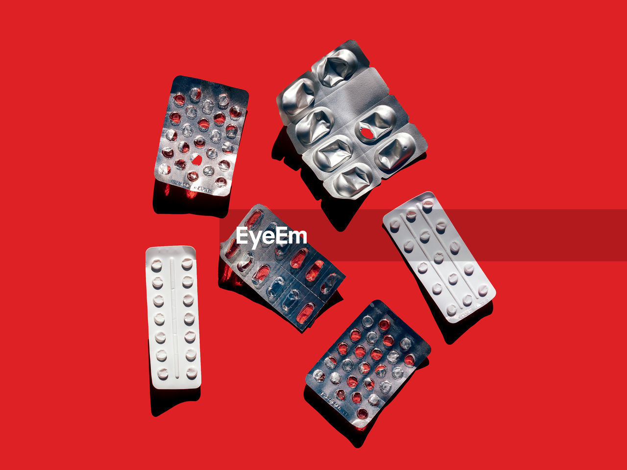 Top view of various empty blister packs of pills for health care placed on red background in light studio during health treatment