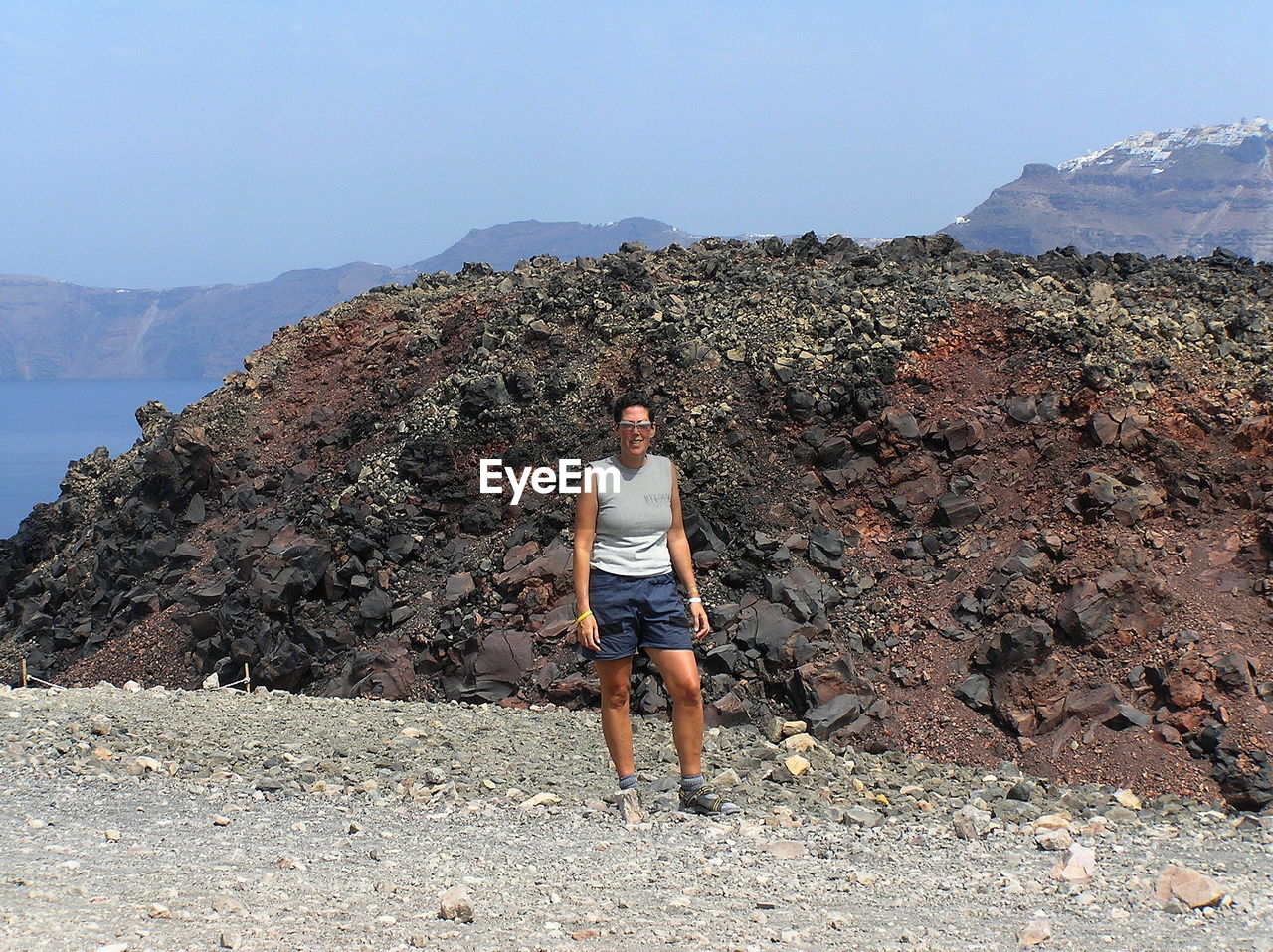 Woman standing against rock formation on sunny day