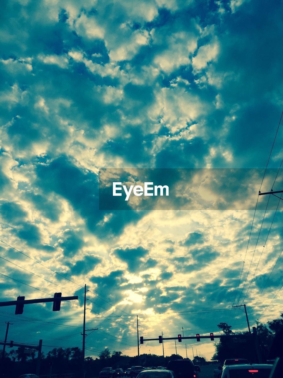 Cars waiting at stoplight against cloudy sky