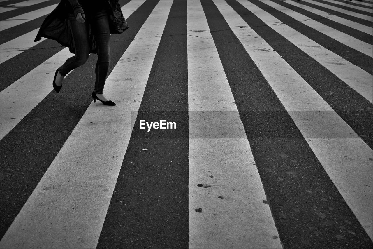 Low section of woman walking on crosswalk