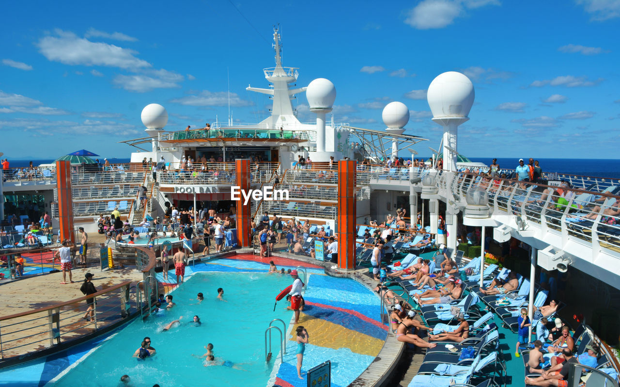 PEOPLE IN SWIMMING POOL AGAINST SKY