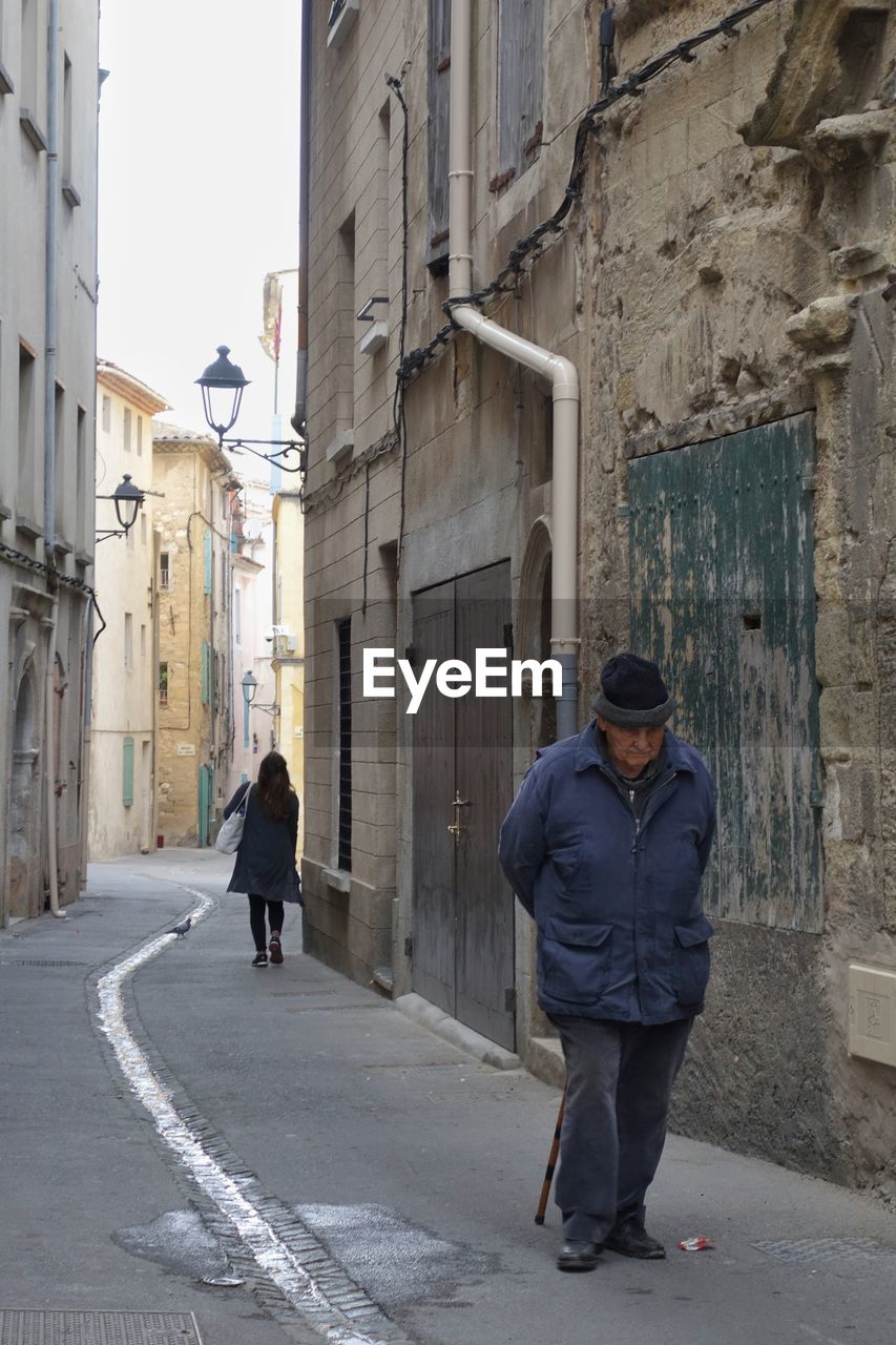 REAR VIEW OF WOMAN WALKING ON STREET