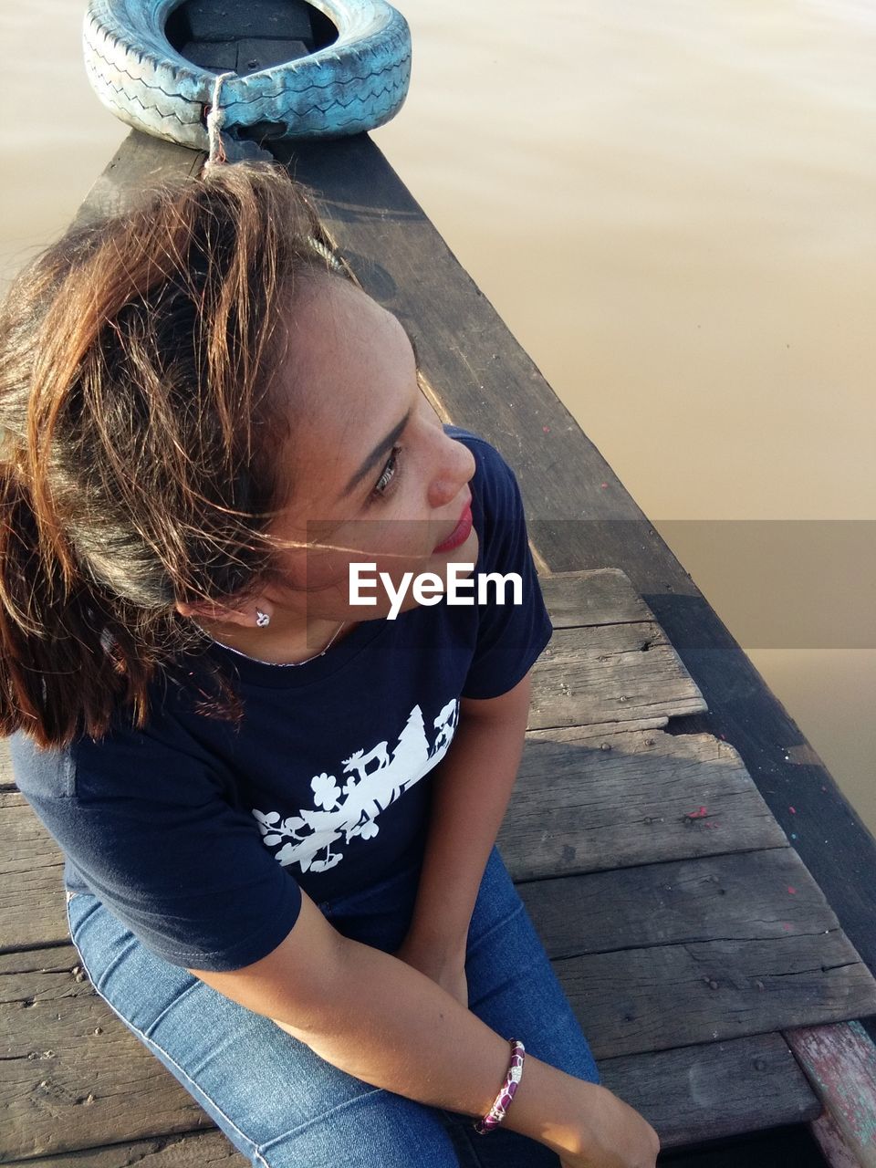 HIGH ANGLE VIEW OF YOUNG WOMAN SITTING AT SHORE