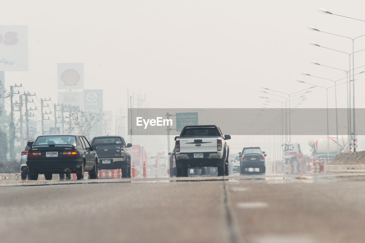 VEHICLES ON ROAD AGAINST BUILDINGS IN CITY