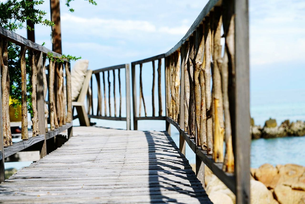 CLOSE-UP OF FOOTBRIDGE OVER SEA AGAINST SKY