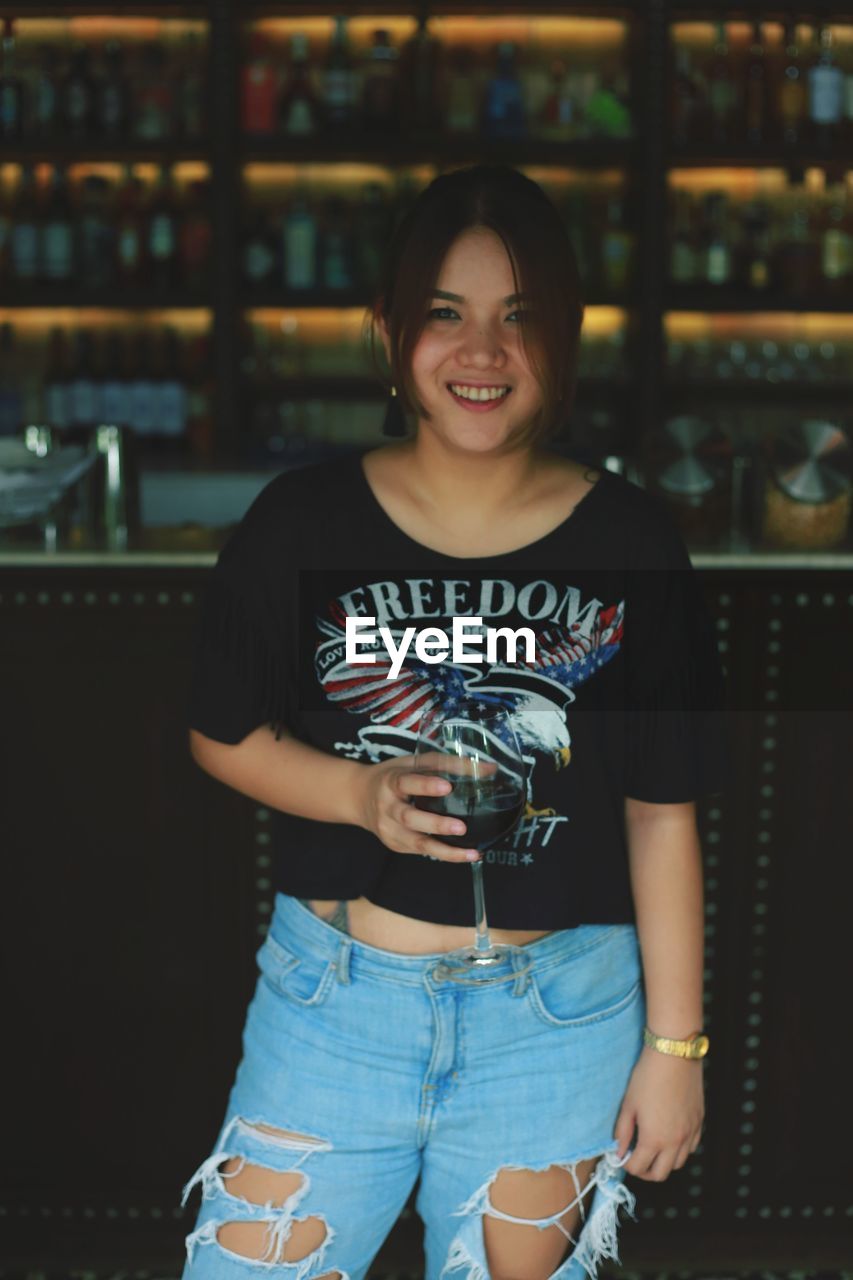 Portrait of smiling young woman standing at restaurant
