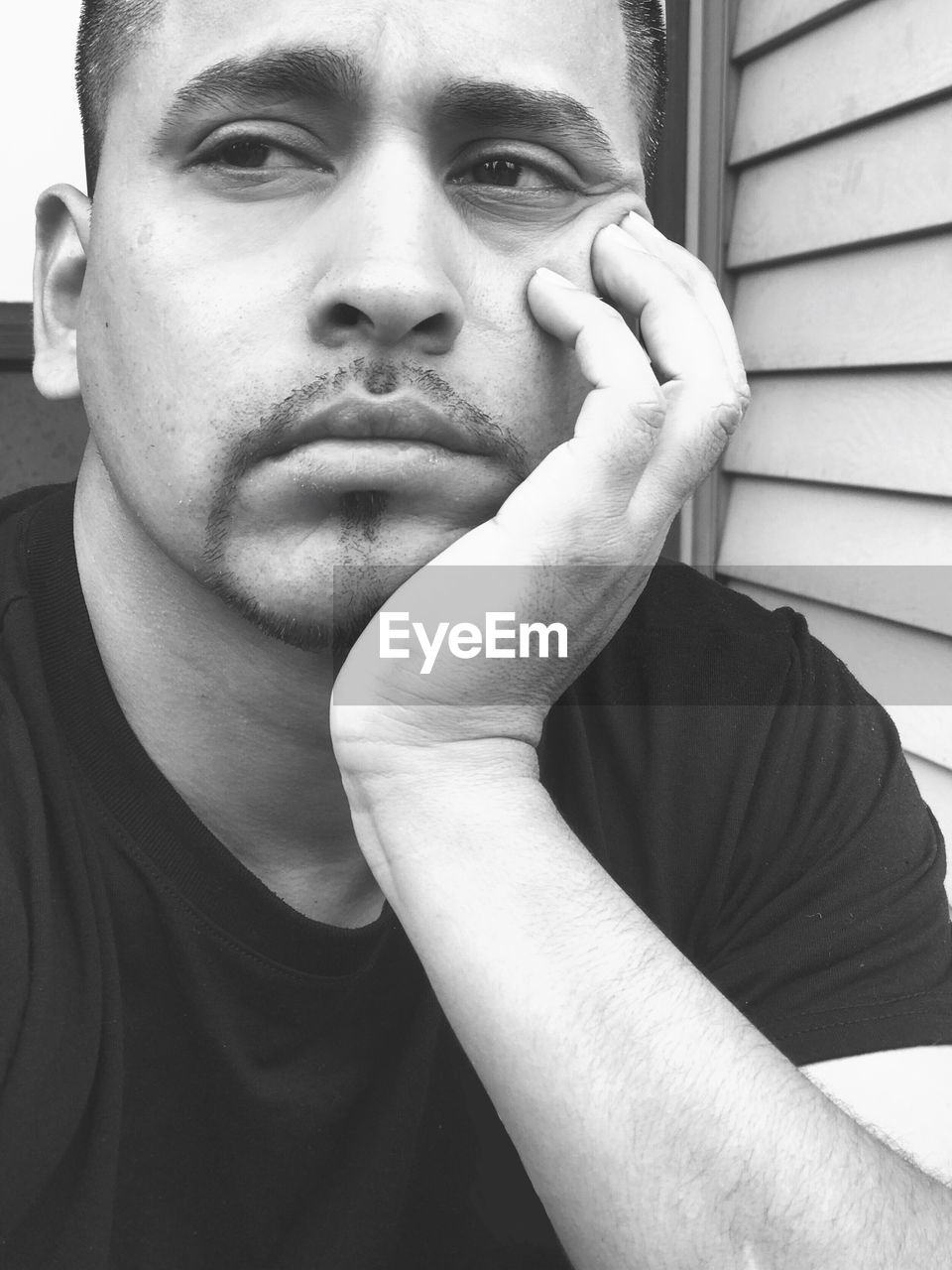 Close-up of bored young man with hand on chin