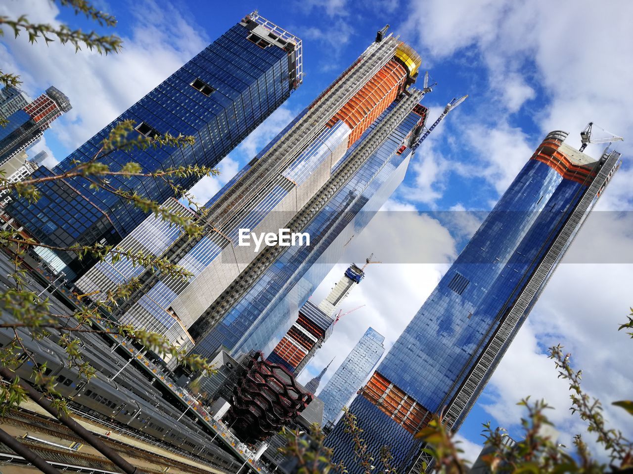 LOW ANGLE VIEW OF BUILDINGS IN CITY AGAINST CLOUDY SKY