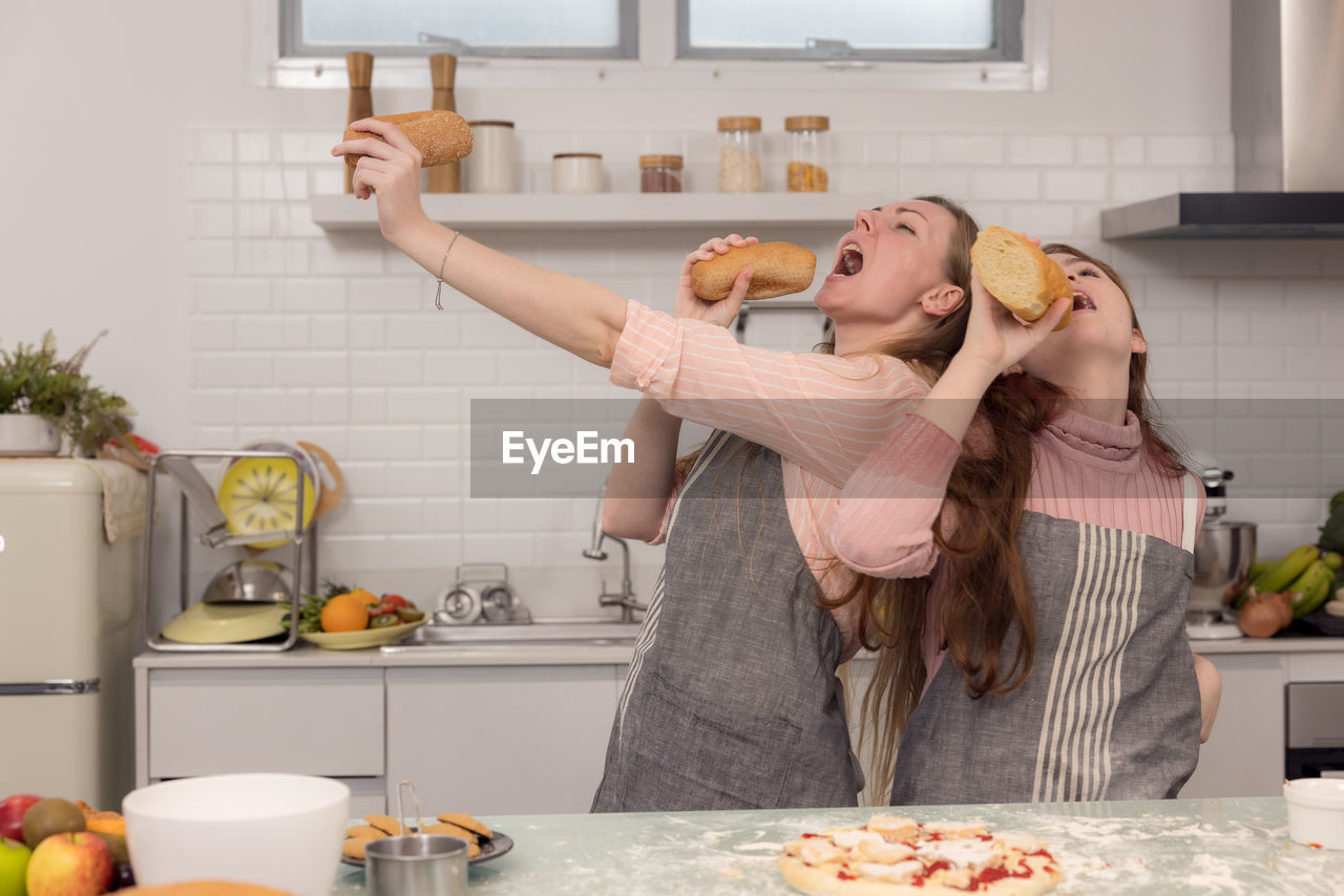 Mother and daughters use bread to sing and entertain one other.