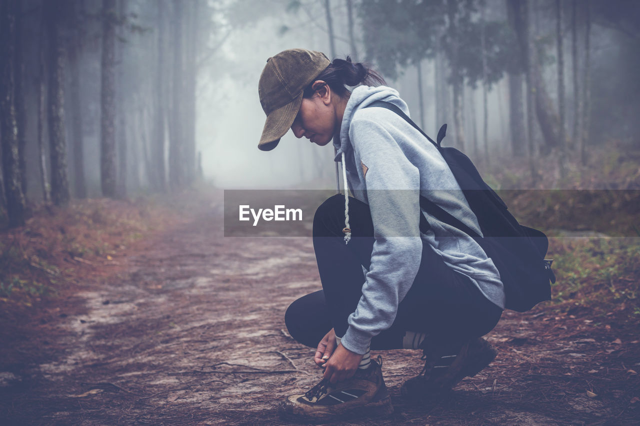 Side view of woman in forest during foggy weather