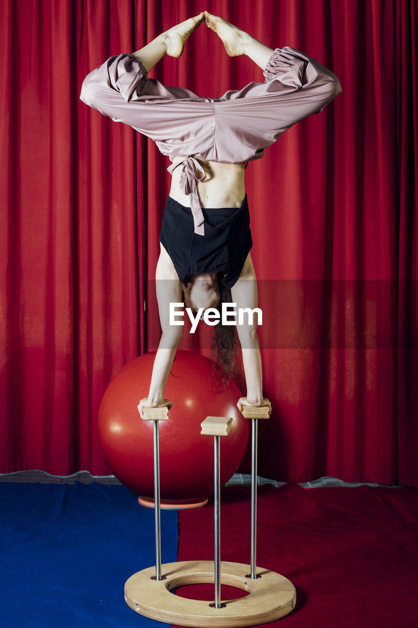 Female performer stretching legs while doing handstand at circus