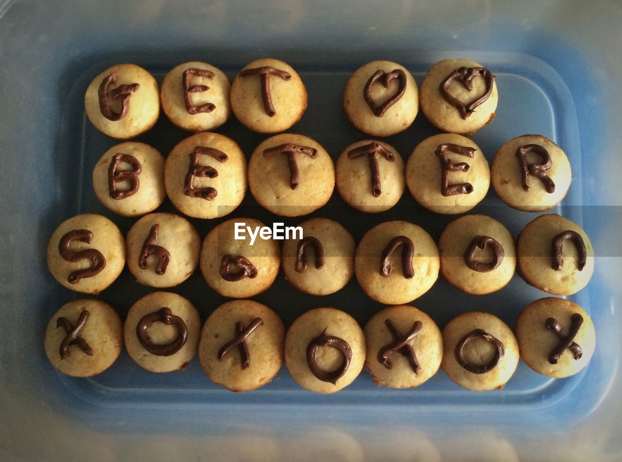 High angle view of chocolate icing text message on vanilla cupcakes in tray