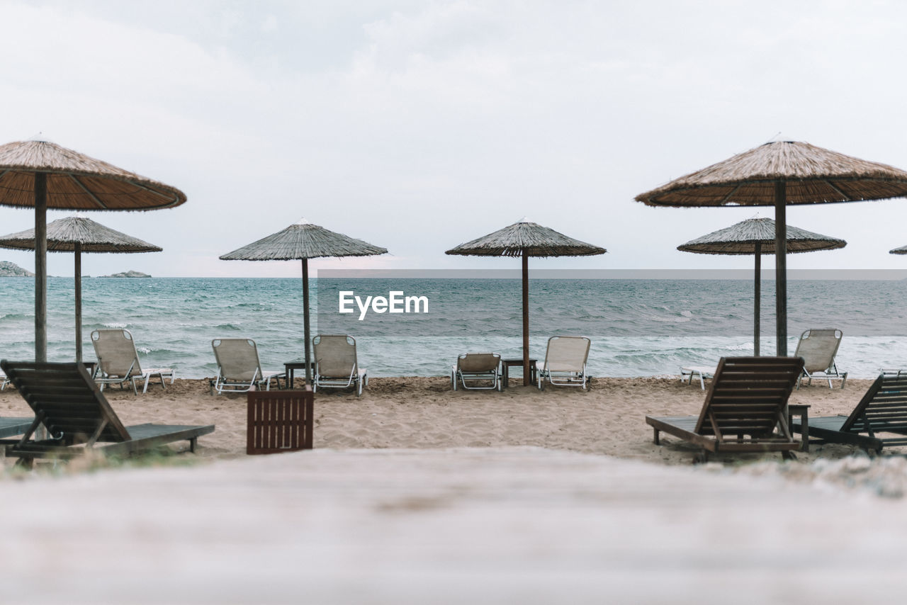 CHAIRS ON BEACH AGAINST SKY