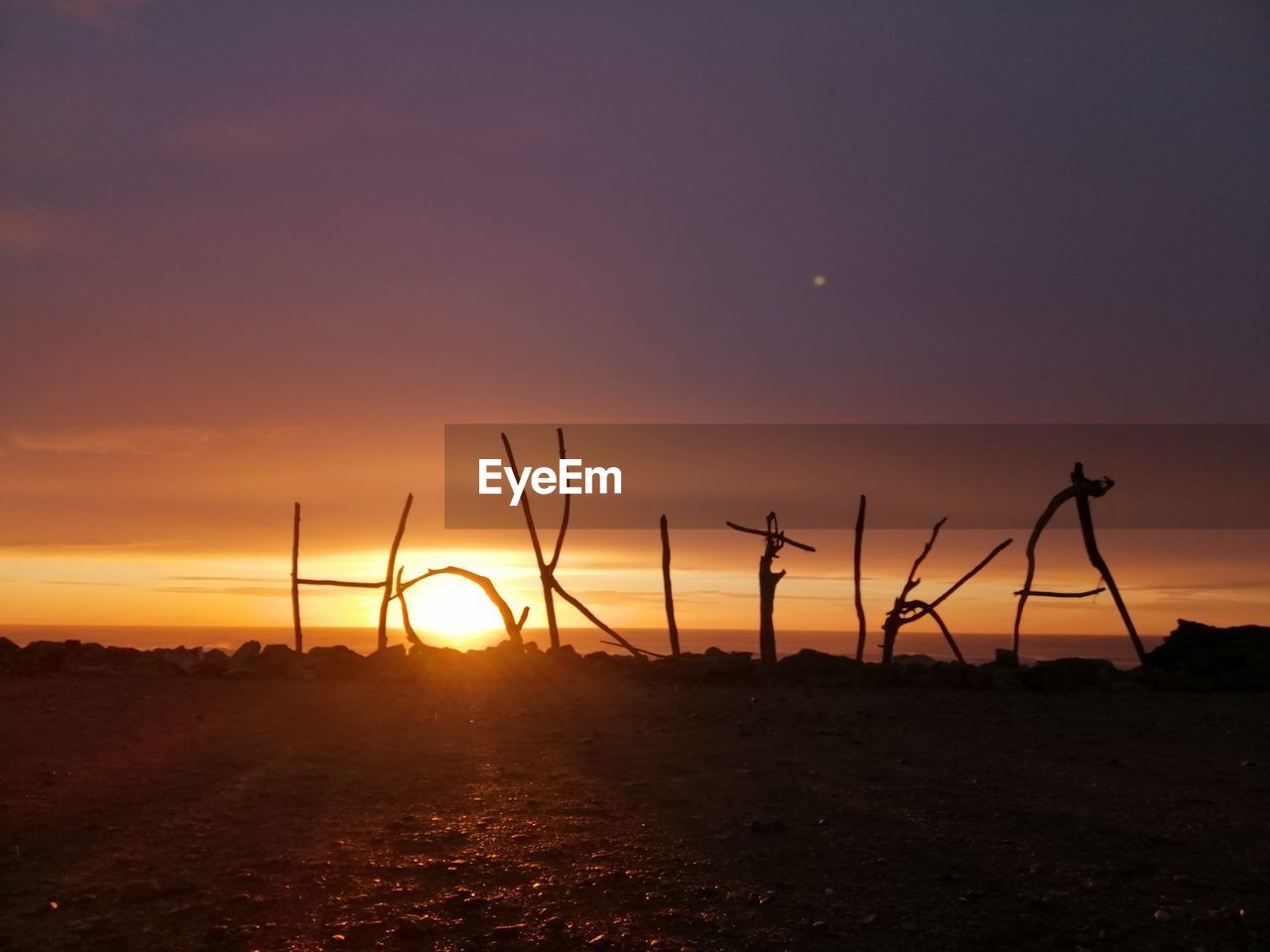 SILHOUETTE FIELD AGAINST SKY AT SUNSET