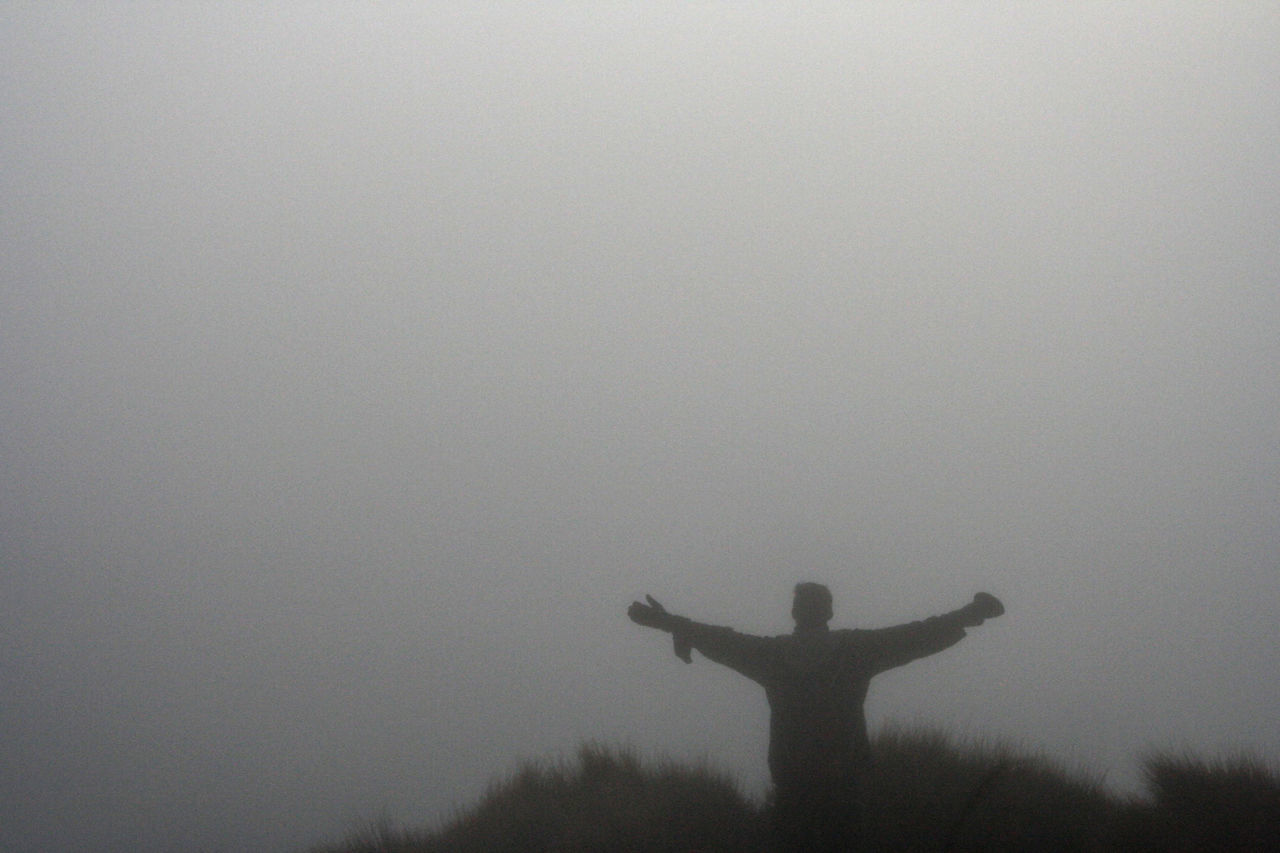 SILHOUETTE MAN WITH ARMS OUTSTRETCHED AGAINST SKY