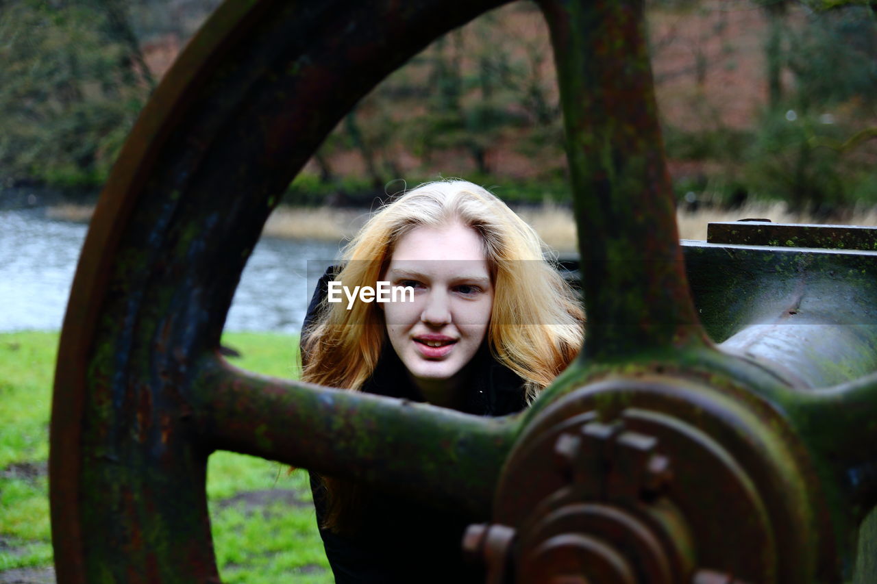 Woman standing behind rusty gear