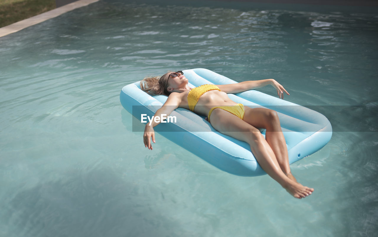 Relaxed young woman lying on an inflatable mattress in the pool