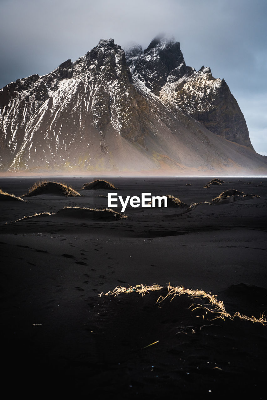 Scenic view of sea by mountains against sky during winter